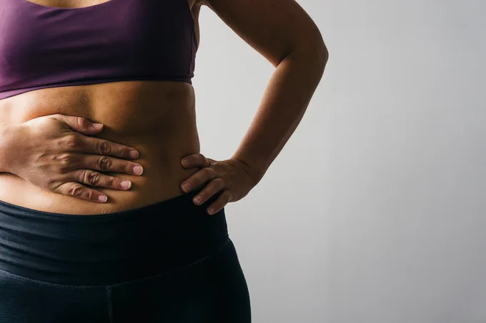 Person holding their lower stomach in pain.