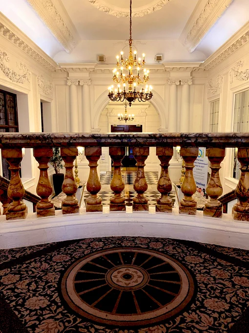 Photo of a beautiful wooden rail at the top of a staircase, with a chandelier above