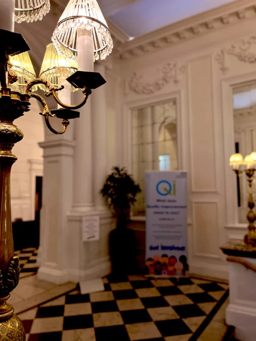 Photo of an ornate lamp with a QI poster in the background