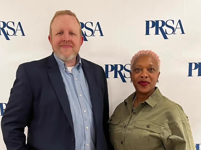 In front of a PRSA Backdrop, Brendan Middleton and Stephanie K. Reed stand together smiling.