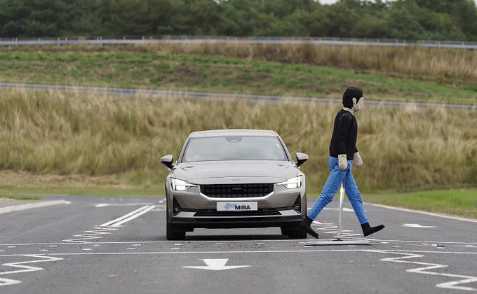 car driving while inflatable pedestrian dummy is crossing the road