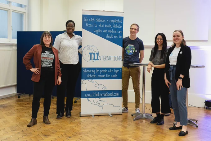 The T1I team standing around a banner with information about T1I.