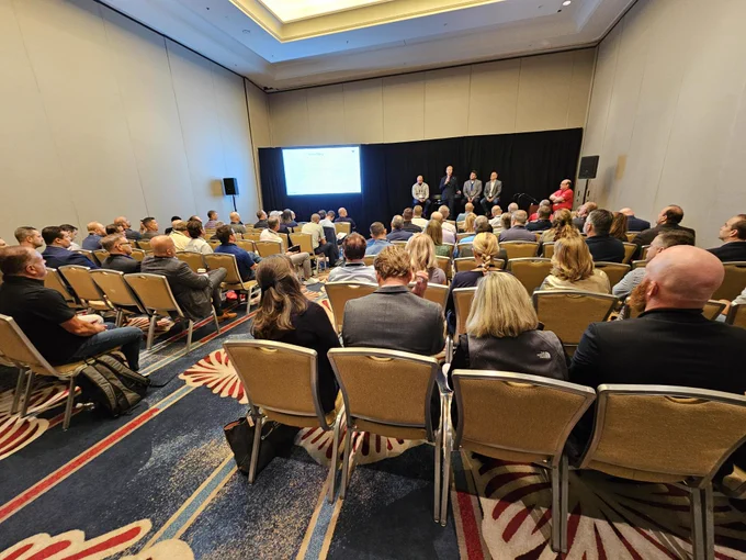 A picture of the room with attendees listening to speakers.