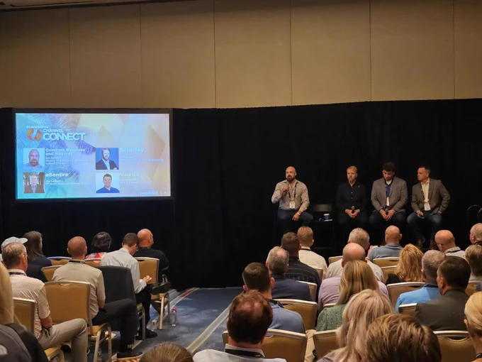 A panel of subject matter experts discuss cybersecurity in front of an audience 