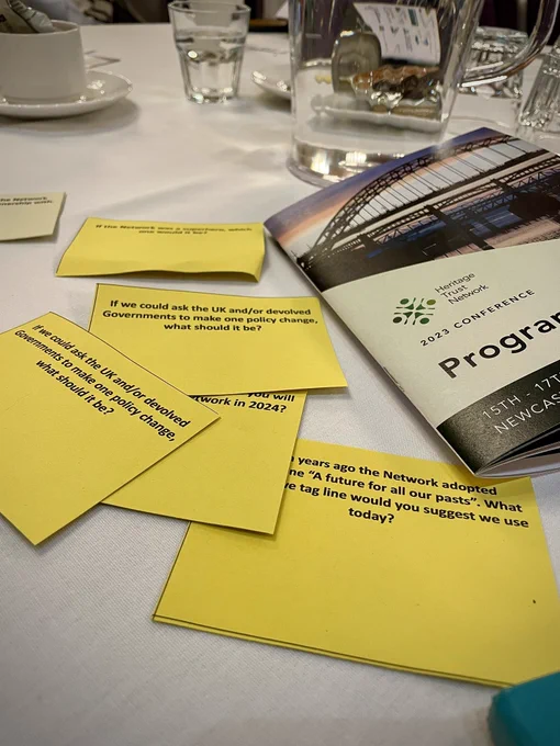Yellow cards with questions printed on them and a conference programme scattered on a table.