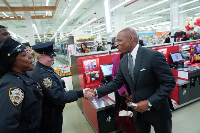 Mayor shakes hands of two officers next to registers inside new target store