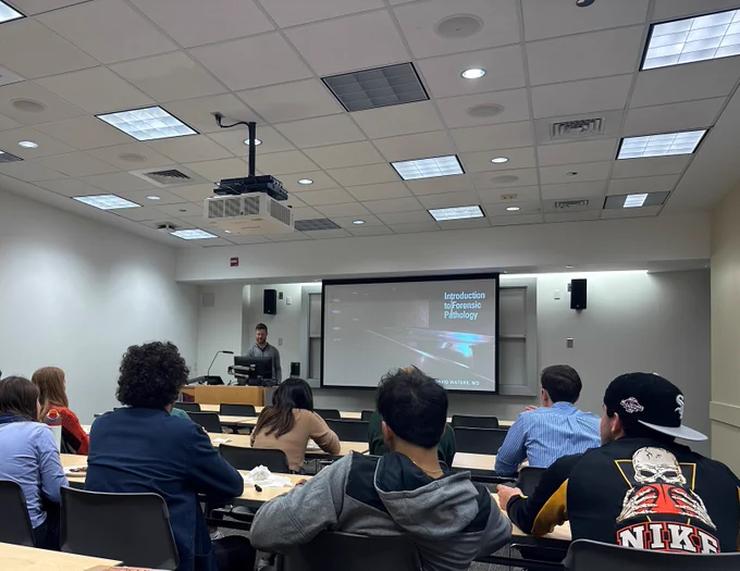 A group of students listen to a lecture from Dr. David Waters on forensic pathology. 