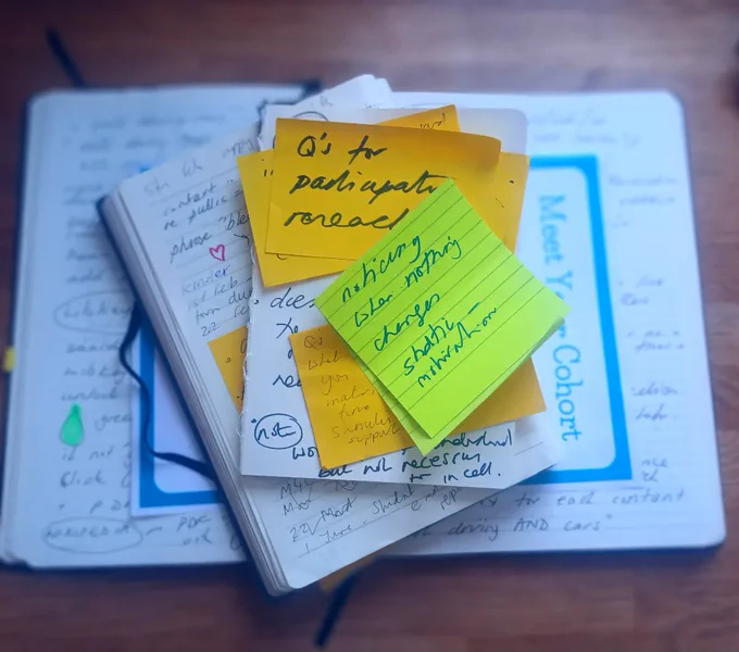 Layers of note books, with green and yellow post it notes seen from above 