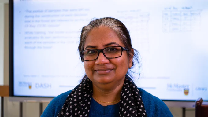 Photo of Shaila Jamal standing in a classroom in front of a projector screen can be seen.