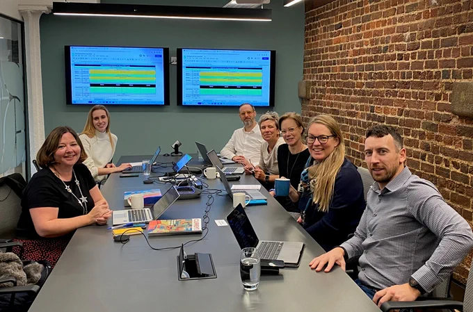 Members of the Planning Committee for the 2024 CASE Development Services conference gather in the CASE Europe office in London. They sit at a board table with laptops.