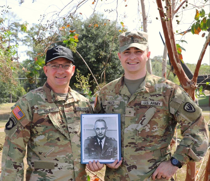 Warrant Officer Charles S. “Scotty” Niles, a flight school student at Fort Novosel, joins his father, retired Chief Warrant Officer 5 Ronald E. “Ron” Niles, a civilian helicopter flight instructor for a three-generations photo, holding a picture of their family member, the late Lt. Col. Gary W. Niles, a retired Army aviator.