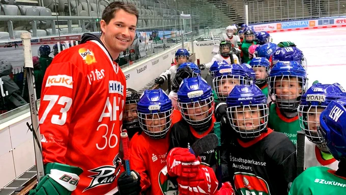 Ein Mann steht mit einer Gruppe von Kindern, die Helme tragen.
