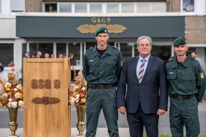 Robert Hemmerling, Dr. Dieter Romann und Jérôme Fuchs stehen neben einem Rednerpult der GSG 9 der Bundespolizei.