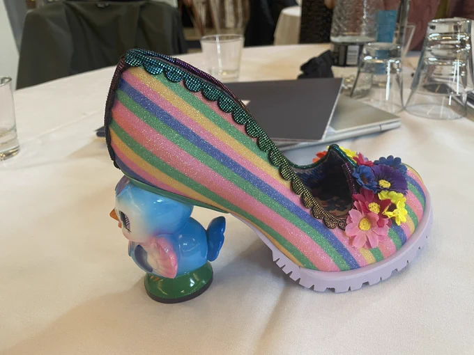 A rainbow shoe with a bird heel and flowers on the front