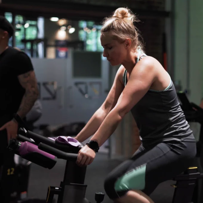 Women cycling on a static bike at a gym spin class.