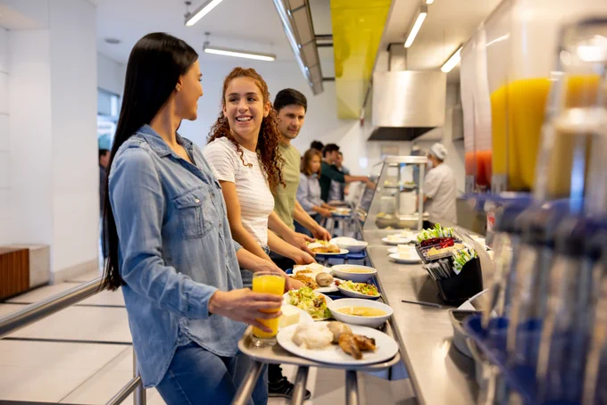 Women chatting happily while queuing to get their lunch at a buffet-style cafeteria