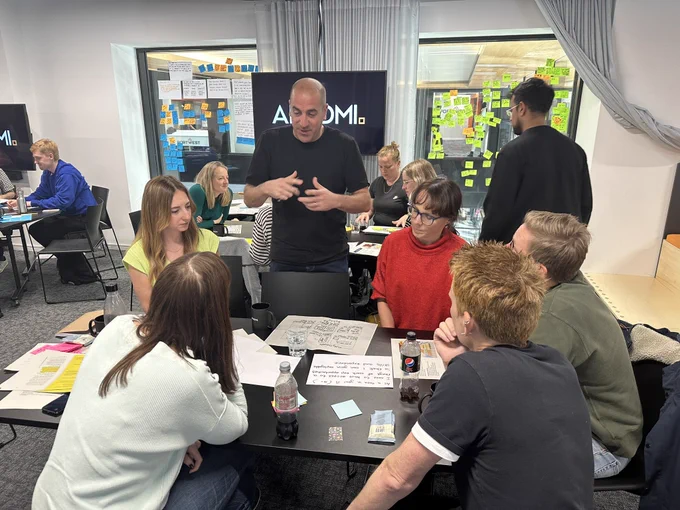 A group of people listen to a description of an idea around a table