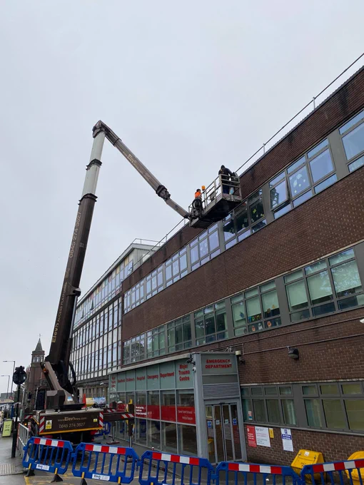 A large elevated platform is set up in front of the Emergency Department at Sheffield Children's. It is black and white and there are two men on the platform. 