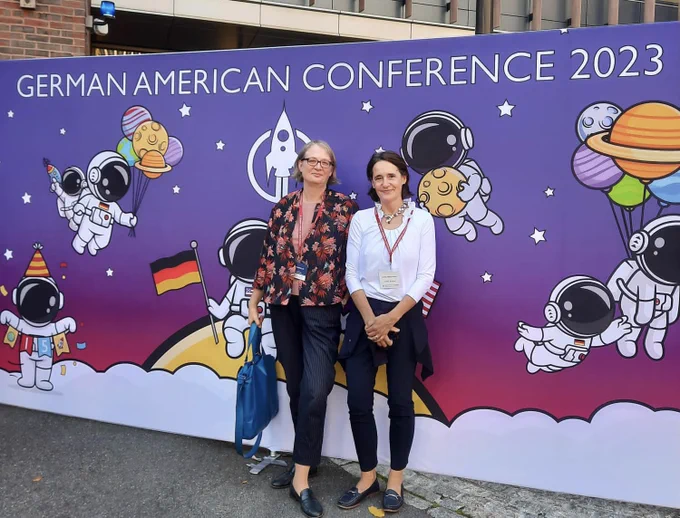 A photo of CG Kreibich and Emily Westhoven in front of. German American Conference banner.
