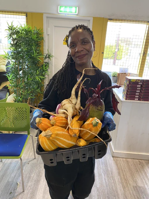 A volunteer smiling at the camera at Mercy In Action, Action Pantry after having washed the donated vegetables.