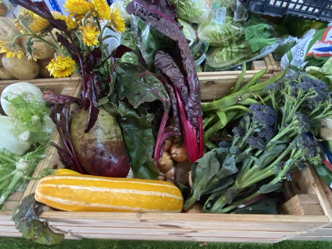 A close-up of the wooden crates at Mercy In Action, Action Pantry containing the vegetables ready to be collected by customers. Visible are beetroot, squash, tenderstem broccoli and runner beans.