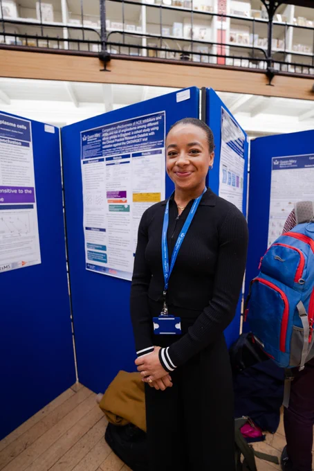 Dr Paris Baptiste standing in front of her poster on William Harvey Day
