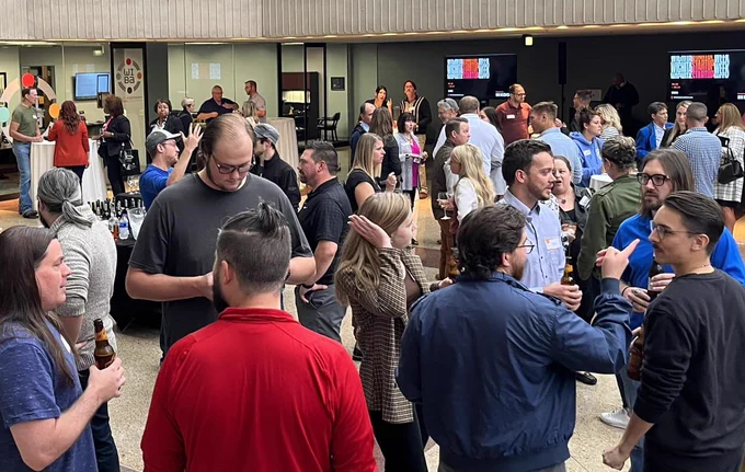 A group of people gathered for a previous event held in association with Wichita Startup Week. A lot of smaller conversations are occurring in the center and tables line the outer edge.