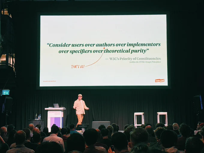Ryan Townsend is giving a presentation at PerfNow and a slide is projected with a quote: "Consider users over authors over implementors over specifiers over theoretical purity"
— W3C's Priority of Constituencies