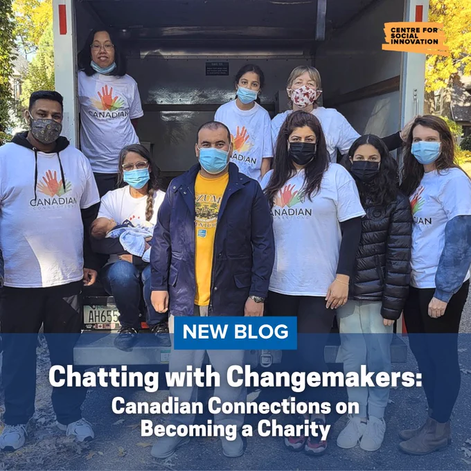 Nine people with Canadian Connections, including founder Marcella Tomas, Executive Director, pose behind a moving truck with an open rear door. Centre for Social Innovation logo in top right. Text overlay, "new Blog. Chatting with Changemakers: Canadian Connections on Becoming a Charity."