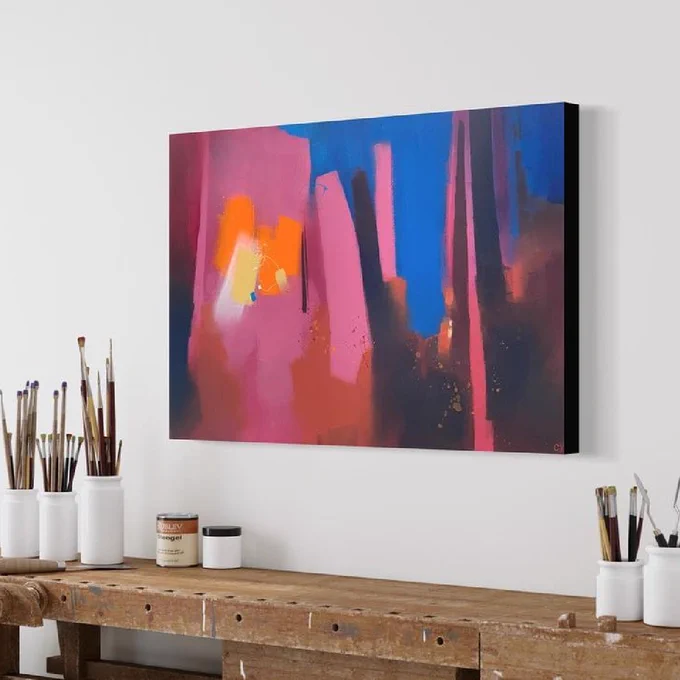 A color piece of abstract art hangs above an artist’s workbench with art supplies.