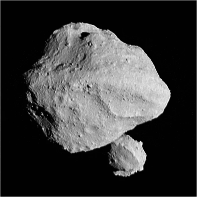 Two asteroids against black space. The larger is a diamond-shaped gray dusty rock lit from the right. The smaller, mostly spherical rock is visible behind the larger’s lower right edge. This image was taken at 11:55 EDT (16:55 UTC) Nov 1, 2023, within a minute of closest approach, from a range of approximately 270 miles (430 km). From this perspective, the satellite is behind the primary asteroid. The image has been sharpened and processed to enhance contrast.

Credit: NASA/Goddard/SwRI/Johns Hopkins APL