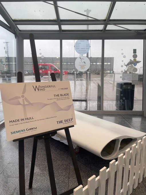 Image of a wind turbine blade section with signage displayed next to it in The Deep's Reception area.
