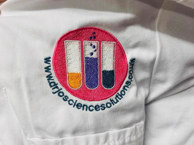Close up of white lab coat pocket with pink embroidered Dr Jo Science logo