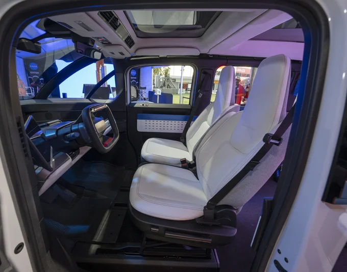 A futuristic interior of a vehicle is shown, with black floors and white seats.
Photo Credit: (NASA/Robert Markowitz)