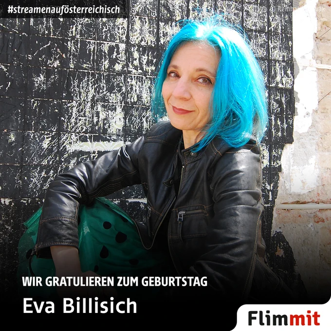 Eine Frau mit blauen Haaren sitzt vor einer Ziegelwand.