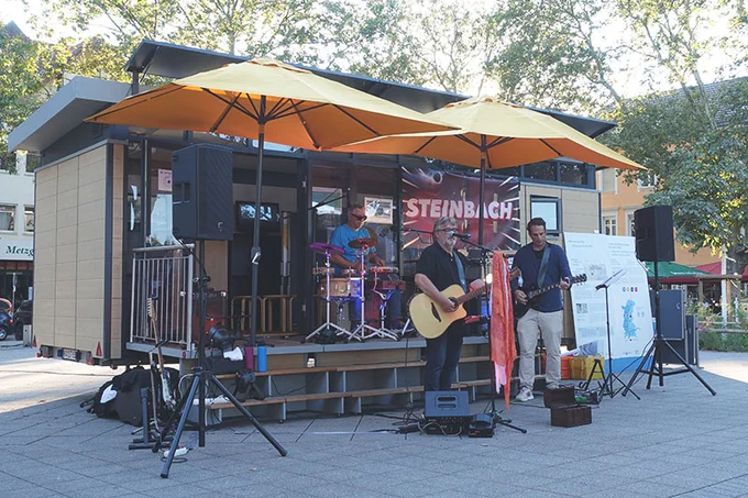Eine Drei-Mann-Band spielt am mobilen Forschungslabor MobiLab Musik.