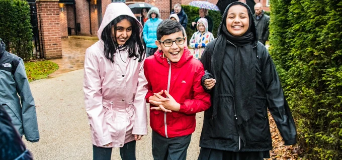 Children smiling and laughing as they walk to school.