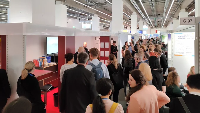 Jan Schilbach hält seinen KI-Vortrag an unserem Messestand. Davor sind viele interessierte Besucherinnen und Besucher.