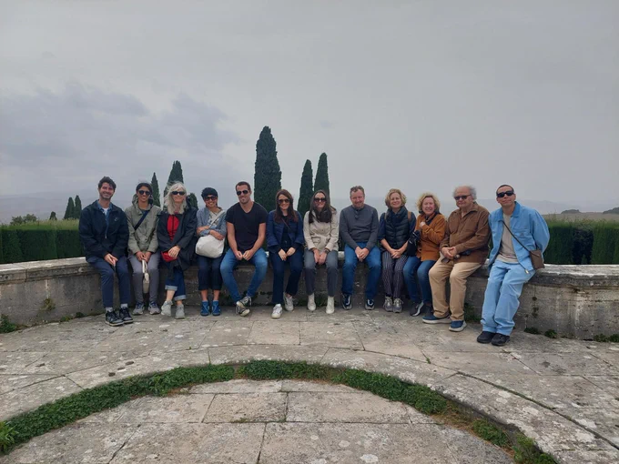 A group of people sitting on a stone bench, Italian countryside behind