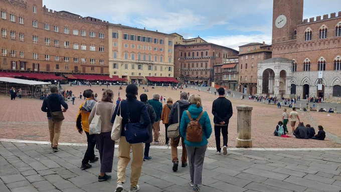 A group of people walking through the main square in Siena, Italy
