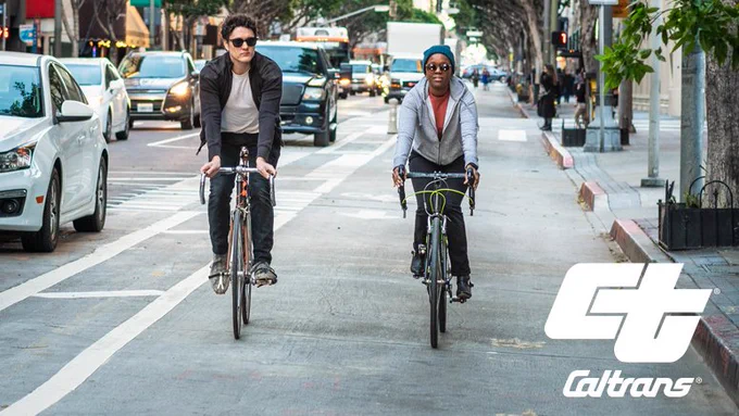 Two people riding bicycles in an urban setting bike lane with the catrans logo overset. 