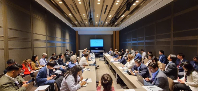 Group of approx 40 people in business attire in long conference room. Screen at the back of the room.