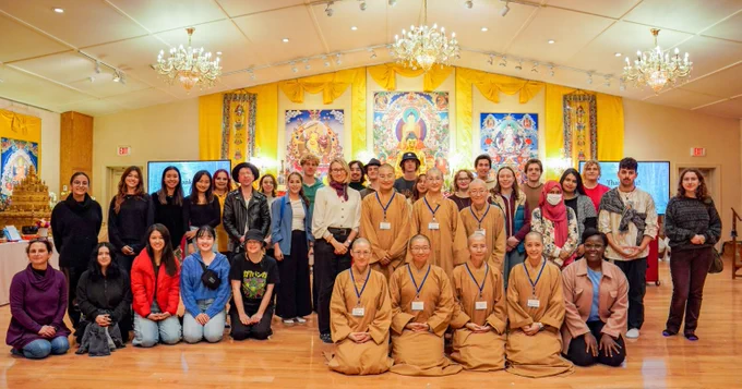 Group photo of university students and Buddhist nuns in a prayer hall.