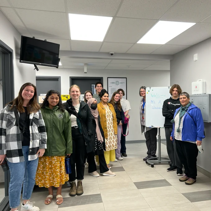 Group photo of university students and hosts in a hallway of an office space.