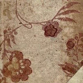 Close-up views of a decorative paper book binding, showing details of flowers and vines printed in deep red ink on a beige background.