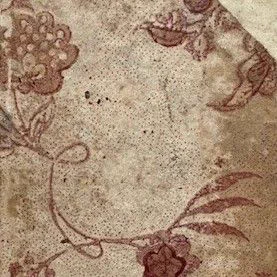 Close-up views of a decorative paper book binding, showing details of flowers and vines printed in deep red ink on a beige background.