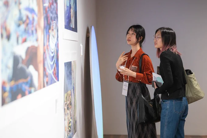 Two women looking at infinite colours artwork and the art posters nearby