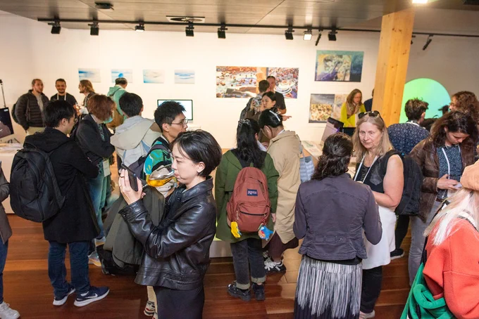 Various groups mingling over drinks next to artworks 