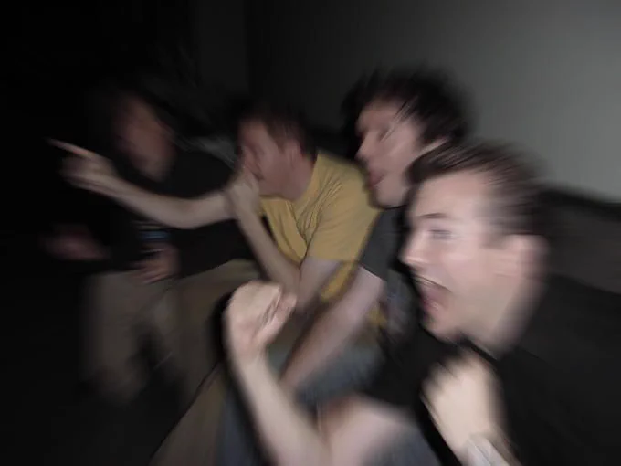 Four people sitting on a couch point and shout in excitement. A camera blur is overlayed to give the appearance of speed.