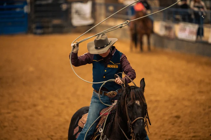 A person riding a horse swings a lasso during a rodeo event.